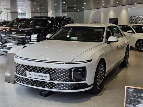 흰색 그랜저 하이브리드를 왼쪽 앞에서 본 모습(전시장 안, 번호판 자리에 'GRANDEUR Hybrid' 전시용 판)