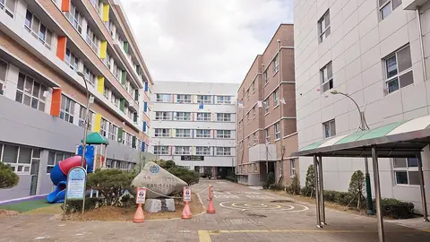 주촌초등학교 정문 안쪽에서 본 교사동 건물들과 교훈 돌, 놀이기구