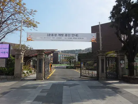 돌기둥 네 개로 된 옛 탑골공원 정문과 그 뒤로 보이는 서울대학교사범대학부설초등학교 운동장과 교사