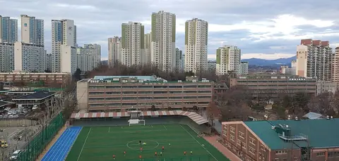 아파트 단지 사이에 있는 배재중학교 건물과 인조잔디 운동장