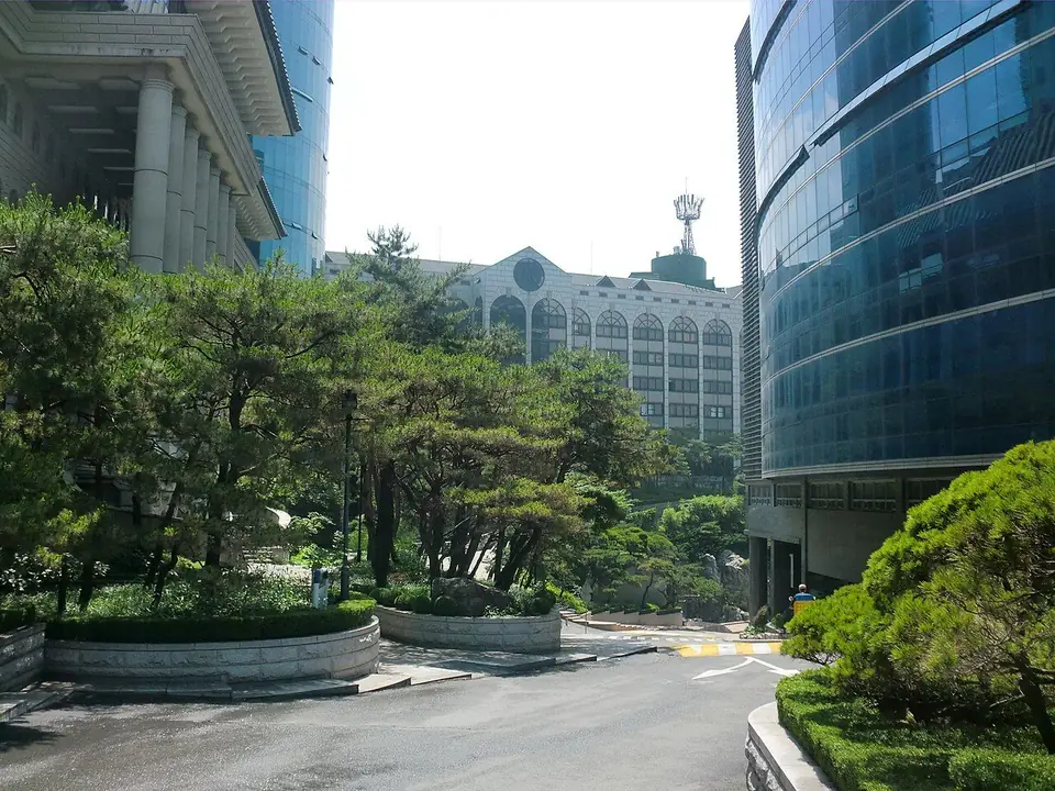 소나무 길 양옆으로 기와지붕 건물과 파란 유리 건물이 서 있는 서경대학교 캠퍼스
