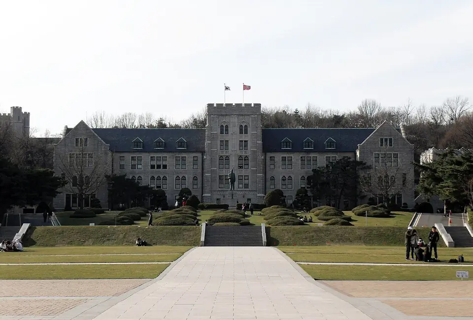 가운데 탑이 있는 회색 석조 건물인 고려대학교 본관과 앞쪽 잔디 광장