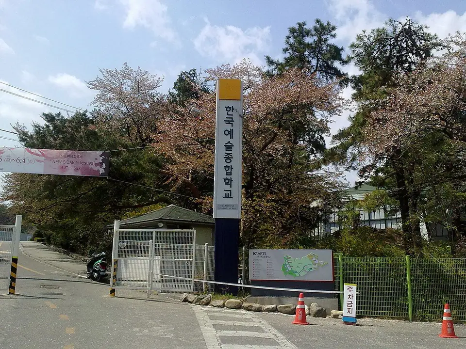 벚꽃 핀 나무 사이로 ‘한국예술종합학교’ 세로 교명 기둥과 교문, 캠퍼스 안내도가 보이는 모습