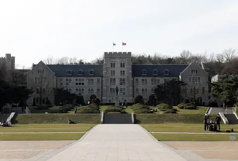 가운데 탑이 있는 회색 석조 건물인 고려대학교 본관과 앞쪽 잔디 광장