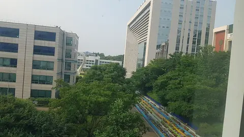 초록 나무 사이로 보이는 가천대학교 글로벌캠퍼스의 높은 건물들