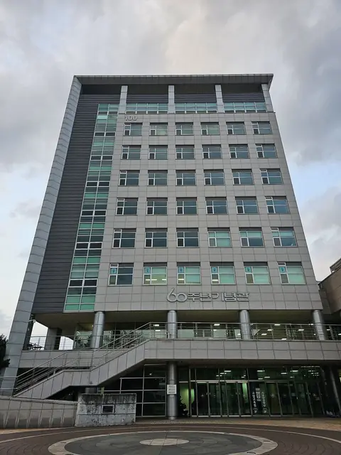 '60주년기념관' 글자가 붙은 회색 고층 건물과 앞쪽 계단·광장