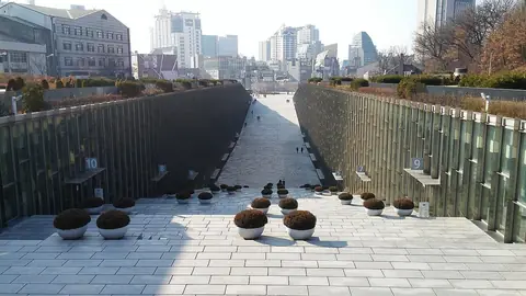 땅을 파낸 듯 양쪽에 유리벽 건물이 있고 가운데로 넓은 돌길이 길게 이어진 캠퍼스