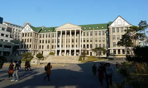 초록 지붕과 흰 기둥이 있는 한양대학교 본관 건물과 앞길(사람들은 멀리서 작게 보임)